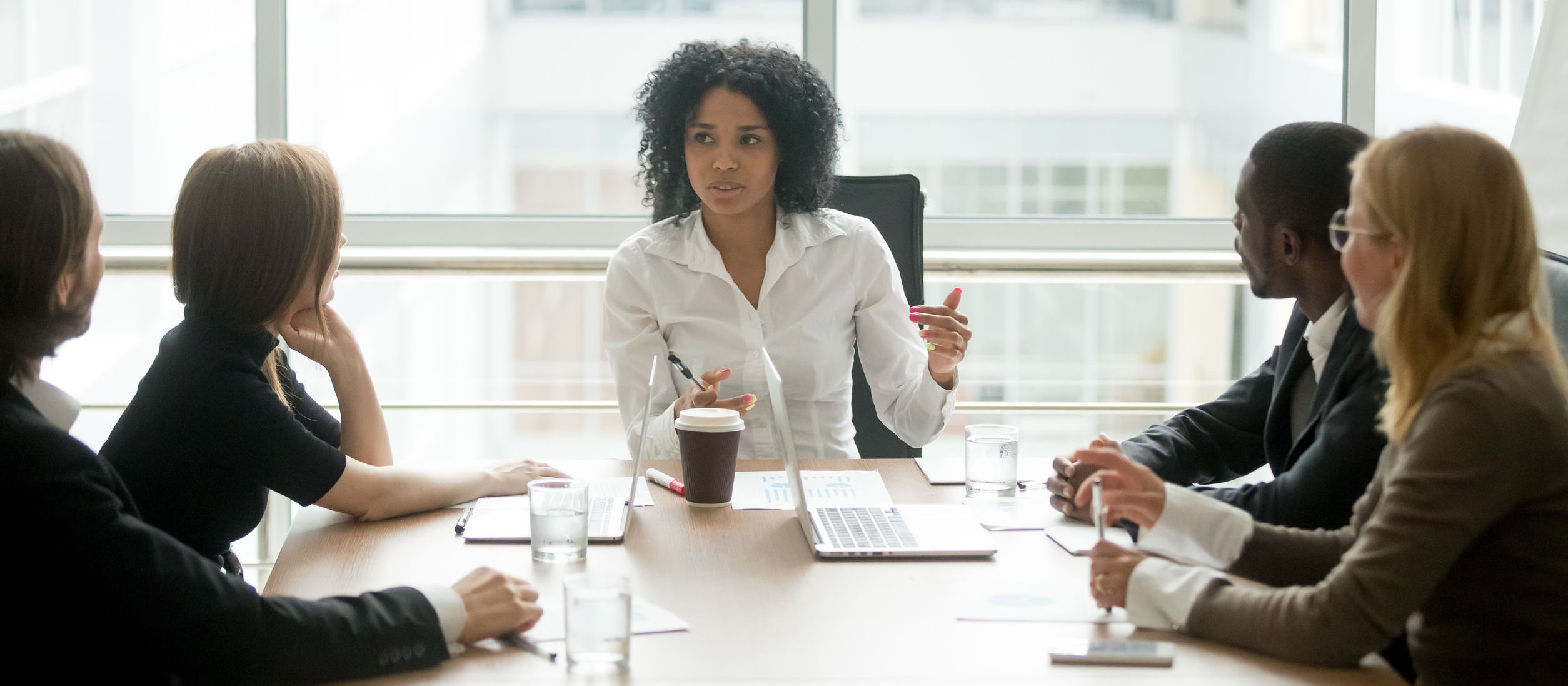 Black female boss leading corporate meeting talking to diverse b